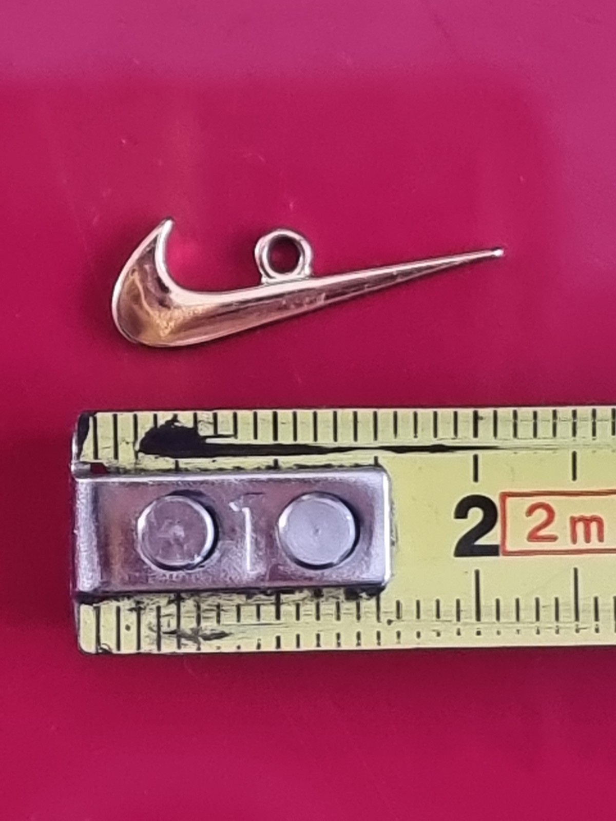 Small Nike tick pendant. Gold-coloured