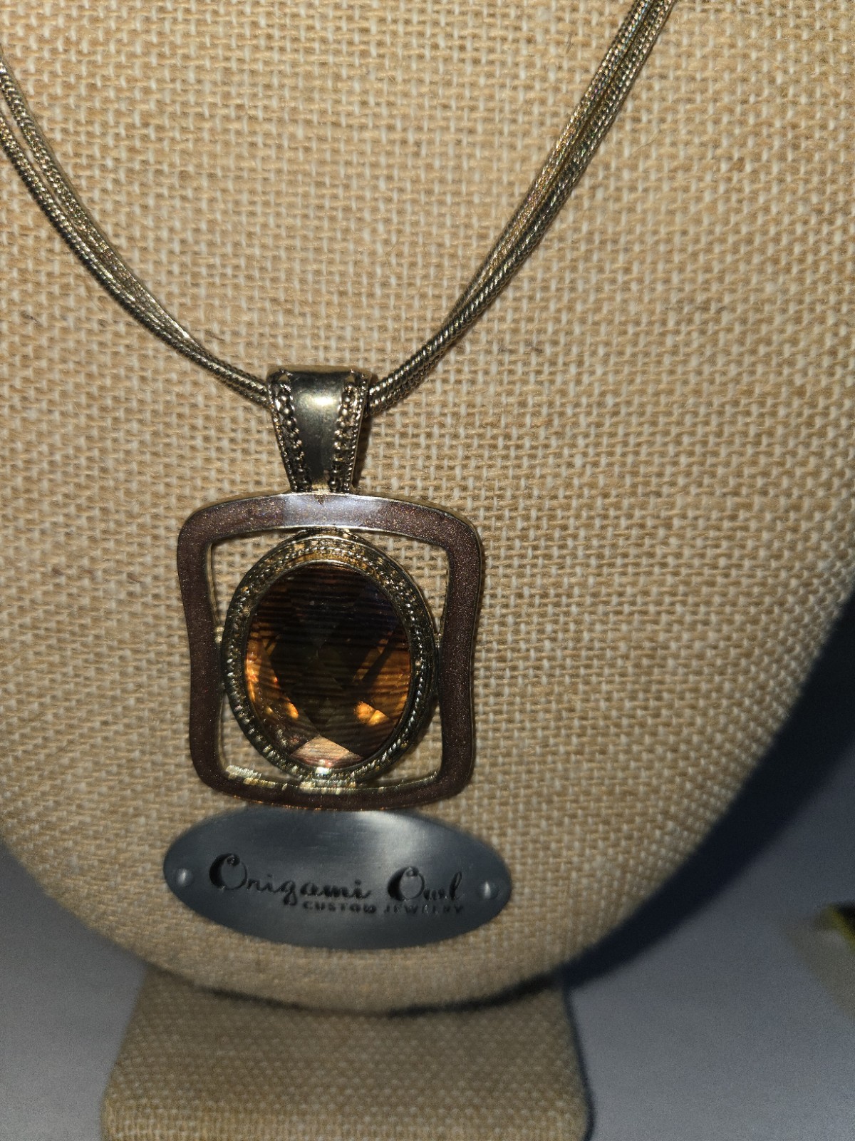 Origami Owl square pendant features a large, faceted oval topaz-colored crystal