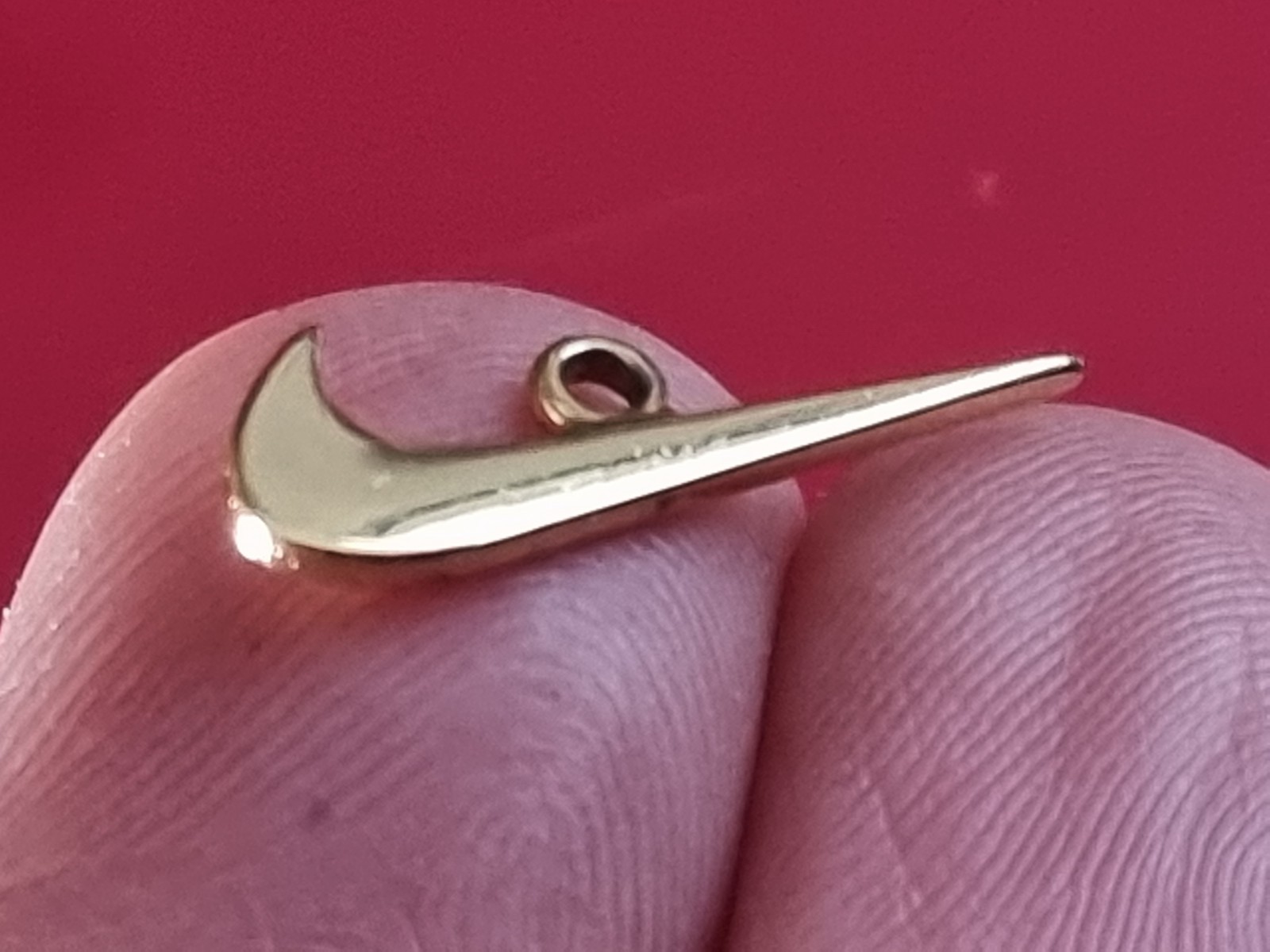 Small Nike tick pendant. Gold-coloured