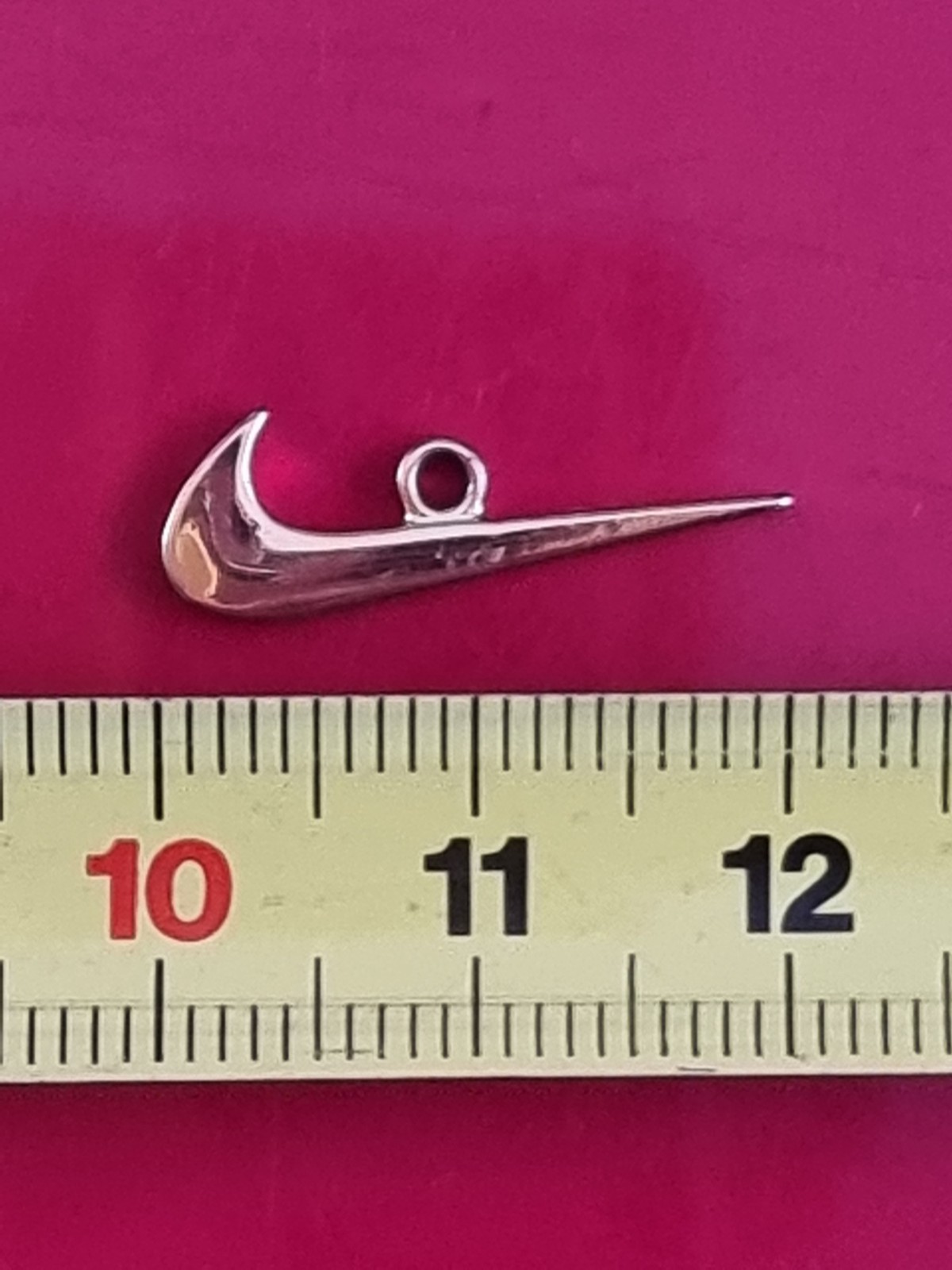 Small Nike tick pendant. Gold-coloured
