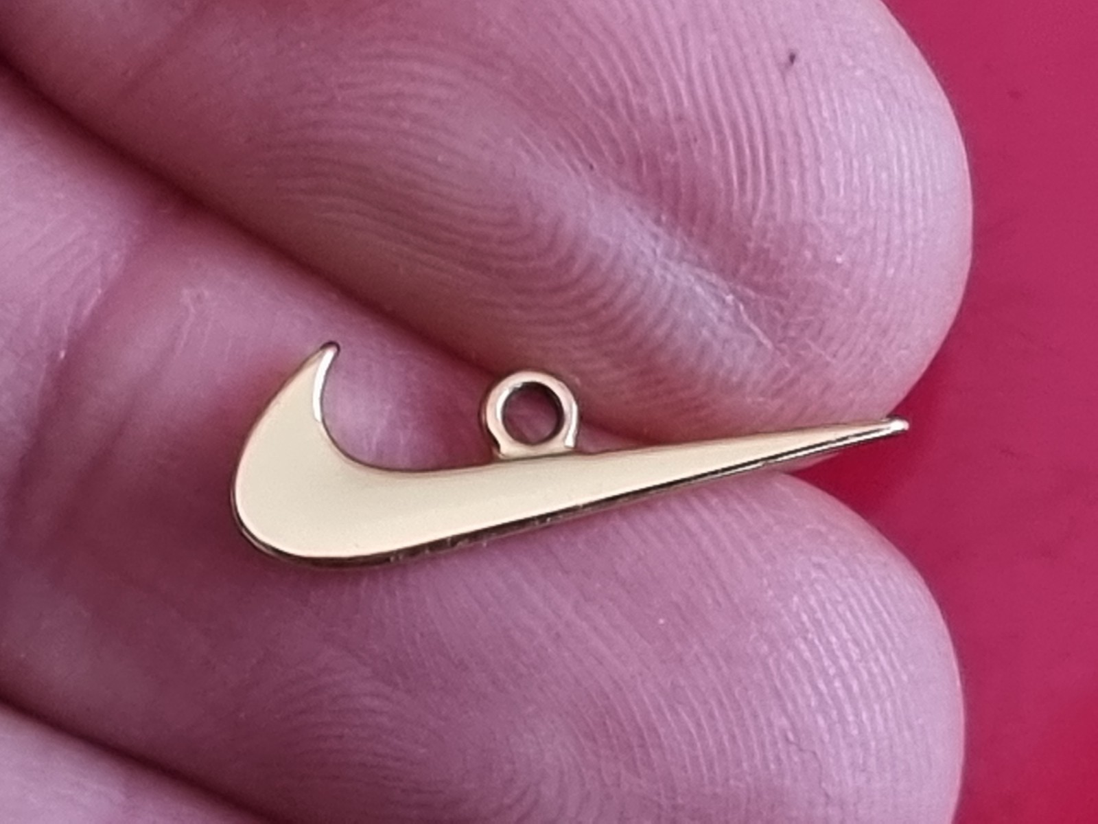 Small Nike tick pendant. Gold-coloured