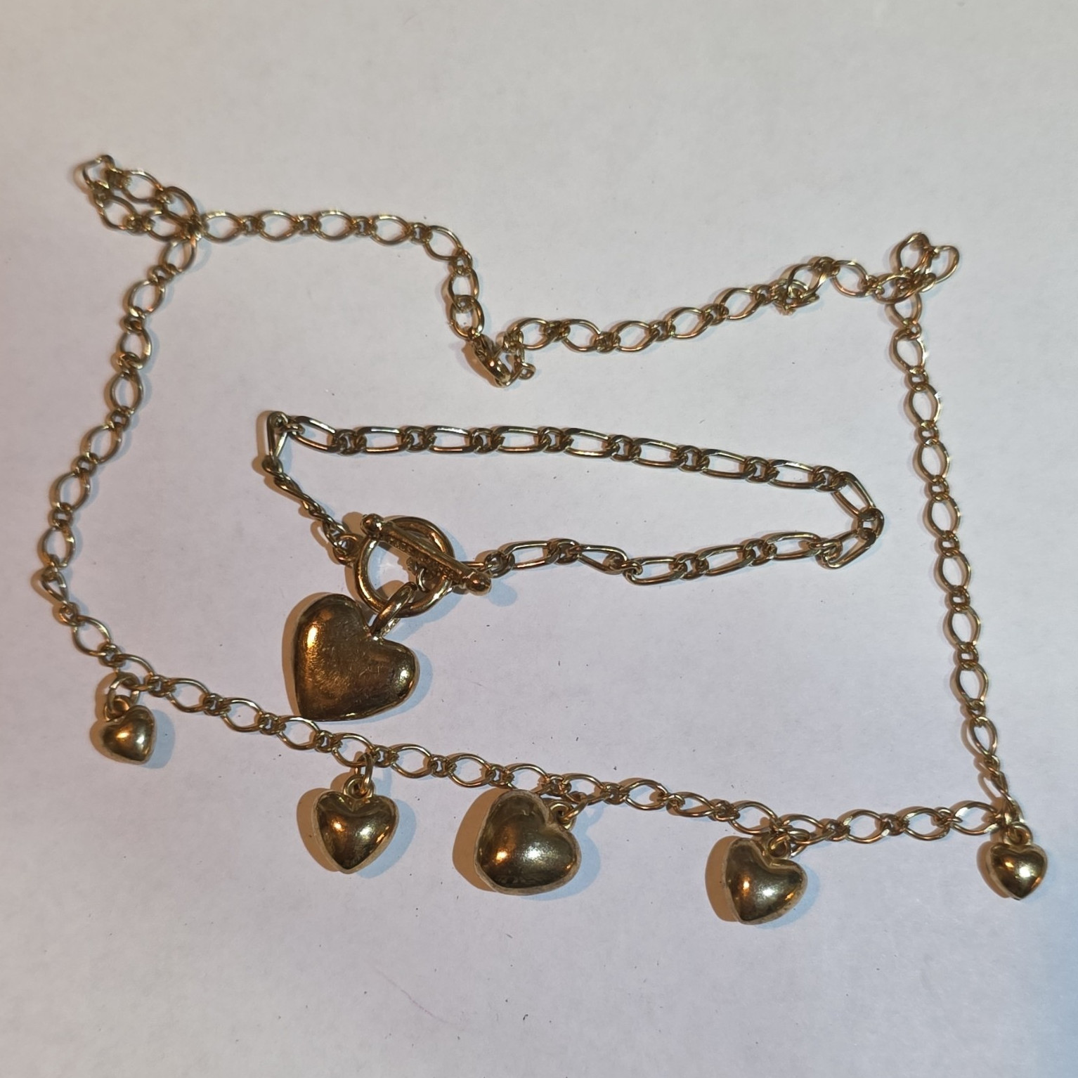 gold heart charm necklace with heart-shaped pendants, matching bracelet