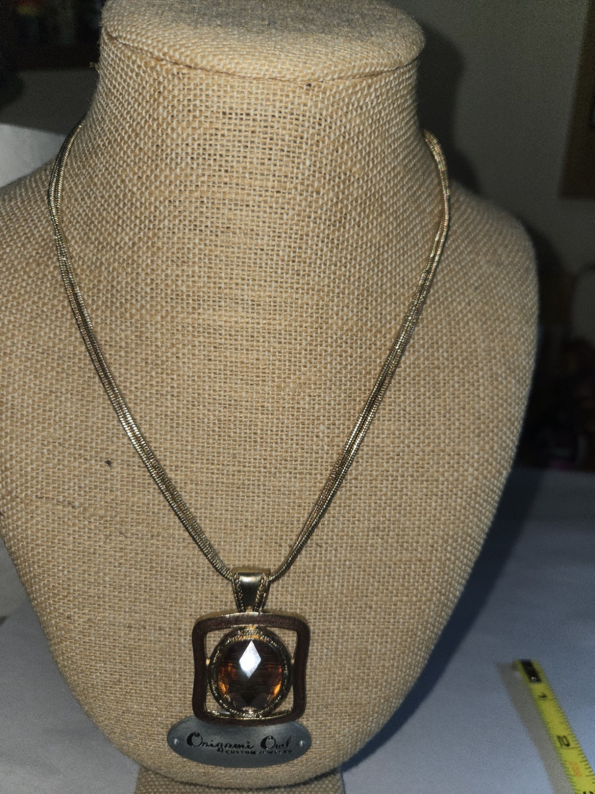 Origami Owl square pendant features a large, faceted oval topaz-colored crystal